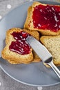 Fresh toasted cereal bread slices with homemade cherry jam and knife on grey plate closeup on grey linen napkin background Royalty Free Stock Photo