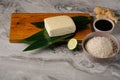 Fresh tofu on bamboo leaves, on a wooden board near soy sauce, rice, ginger and lime. Royalty Free Stock Photo