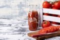Fresh tomato juice in a glassware. A glass mug of tomato juice. Tomatoes in a box and sliced tomatoes on a wooden board. Space for