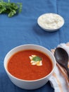 Fresh tomato soup. Seasonal summer dish. Located on a blue linen tablecloth. Nearby lies a spoon on a white cotton napkin. Bread Royalty Free Stock Photo