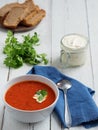 Fresh tomato soup. Seasonal summer dish. Located on a vintage white background. Nearby is a spoon on a blue cotton napkin. Bread Royalty Free Stock Photo