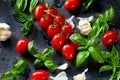 Fresh tomatoes with basil garlic and sea salt on black slate background Royalty Free Stock Photo