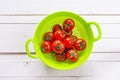 Fresh tomatoes cherry in green colander on the white painted woo Royalty Free Stock Photo