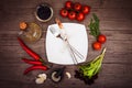 Fresh tomatoes, chili pepper and other spices and herbs around modern white square plate in the center of wooden table. Royalty Free Stock Photo