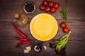 Fresh tomatoes, chili pepper and other spices and herbs around modern yellow plate in the center of wooden table. Top view. Copy Royalty Free Stock Photo