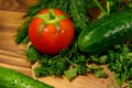 Fresh tomatoes, cucumbers, parsley and dill on cutting board on wooden table Royalty Free Stock Photo