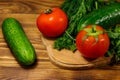 Fresh tomatoes, cucumbers, parsley and dill on cutting board on wooden table Royalty Free Stock Photo