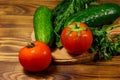 Fresh tomatoes, cucumbers, parsley and dill on cutting board on wooden table Royalty Free Stock Photo