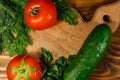 Fresh tomatoes, cucumbers, parsley and dill on cutting board on wooden table Royalty Free Stock Photo