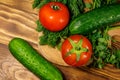 Fresh tomatoes, cucumbers, parsley and dill on cutting board on wooden table Royalty Free Stock Photo