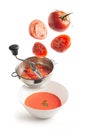 Fresh tomatoes flying, masher with crushed tomato and bowl with tomato cream