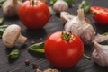 Fresh tomatoes and garlic closeup on dark rustic wood Royalty Free Stock Photo