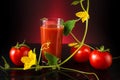 Fresh tomatoes and a glass full of tomato juice. Tomatoes and cucumbers lie on a black reflective table with a dark background and Royalty Free Stock Photo