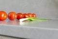 Fresh tomatoes and green onions plucked from the garden are on the gray, working surface of the kitchen