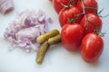 Fresh tomatoes, onions and pickles on plastic cutting board Royalty Free Stock Photo