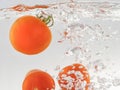 Fresh tomatoes are thrown into the water with splashes. Close-up