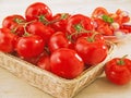 Fresh tomatoes in a wicker basket on table Royalty Free Stock Photo