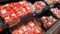 Fresh tomatoes wrapped in cellophane containers on display.