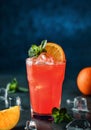 Fresh tropical cocktail with orange, mint and ice in glass on dark blue background. Summer cold drink and cocktail. Royalty Free Stock Photo