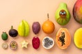 Fresh tropical whole and halved fruits on a beige background making a row.