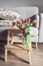 Fresh tulips bouquet in vase are in living room. Cozy home decor Royalty Free Stock Photo