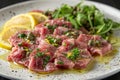 Fresh Tuna Carpaccio with Lemon Slices, Capers, and Arugula on Elegant Dark Plate