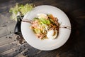 Fresh Tuna salad with eggs, tomatoes, beans, olives on white plate.