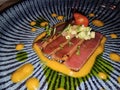 Fresh tuna sashimi served with vibrant sauce and garnished with cherry tomato and herbs in a creative Royalty Free Stock Photo