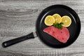 Fresh tuna steak with slices of lemons in skillet. Royalty Free Stock Photo