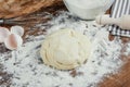 Fresh unbaked dough in flour on wooden table top