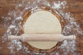 Fresh unbaked dough with rolling pin on wooden board