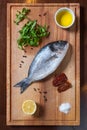 Fresh uncooked dorado fish with ingredients on the wooden board
