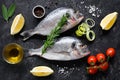 Fresh uncooked dorado or sea bream fish with lemon slices, spices, herbs and vegetables. Mediterranean food. Top view Royalty Free Stock Photo