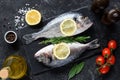 Fresh uncooked dorado or sea bream fish with lemon slices, spices, herbs and vegetables. Mediterranean food. Top view Royalty Free Stock Photo