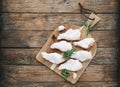 Raw chicken wings with skin on cutting board with ingredients for cooking at wooden background. Fresh uncooked drumette Royalty Free Stock Photo