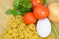 Fresh uncooked gold colored pasta, tomatoes, egg, parsley and onion Royalty Free Stock Photo