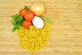 Fresh uncooked gold colored pasta, tomatoes, egg, parsley and onion Royalty Free Stock Photo