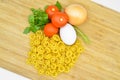 Fresh uncooked gold colored pasta, tomatoes, egg, parsley and onion Royalty Free Stock Photo