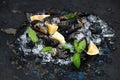 Fresh uncooked mussels with lemon, herbs and spices on chipped ice over dark slate stone backdrop Royalty Free Stock Photo