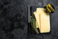 Fresh Uncooked Raclette Swiss cheese slices on marble board. Black background. Top view. Copy space