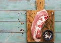 Fresh uncooked raw meat beef brisket on the bone on a green wooden rustic table with spices for cooking. Top view, flat lay. Royalty Free Stock Photo