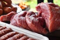 Fresh uncooked red meat, sausages and meatballs on the wooden table ready to be cooked on the outdoor fire grill. Barbecue  in the Royalty Free Stock Photo