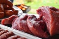 Fresh uncooked red meat, sausages and meatballs on the wooden table ready to be cooked on the outdoor fire grill. Barbecue  in the Royalty Free Stock Photo
