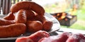 Fresh uncooked red meat, sausages and meatballs on the wooden table ready to be cooked on the outdoor fire grill. Barbecue  in the Royalty Free Stock Photo