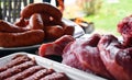 Fresh uncooked red meat, sausages and meatballs on the wooden table ready to be cooked on the outdoor fire grill. Barbecue  in the Royalty Free Stock Photo