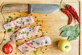 Uncooked pieces of silver carp fish with red chile pepper, bay leaf, apple, spices and knife on wooden board, top view. Royalty Free Stock Photo