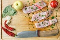 Uncooked pieces of silver carp fish with red chile pepper, bay leaf, apple, spices and knife on wooden board, top view. Royalty Free Stock Photo