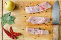 Uncooked pieces of silver carp fish with red chile pepper, bay leaf, apple, spices and knife on wooden board, top view. Royalty Free Stock Photo