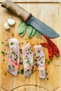 Uncooked pieces of silver carp fish with red chile pepper, bay leaf, garlic, spices and knife on wooden board, top view. Royalty Free Stock Photo