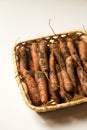 Fresh unwashed carrots in a basket on a white background